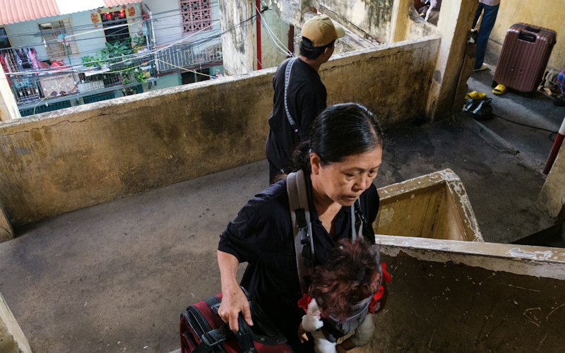 Woman carrying a suitcase up concrete stairs