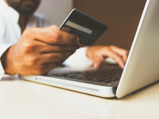 Person holding a bank card while using a laptop