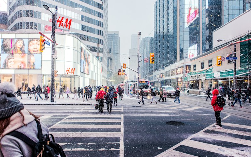 Pedestrians crossing a snowy downtown Toronto intersection